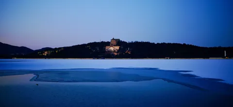 A frozen lake and distant hill at dusk