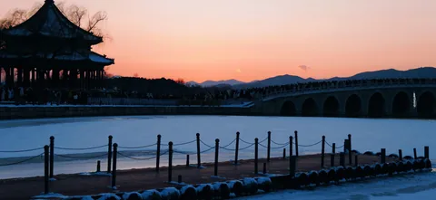 A pavilion and bridge above a frozen lake at sunset