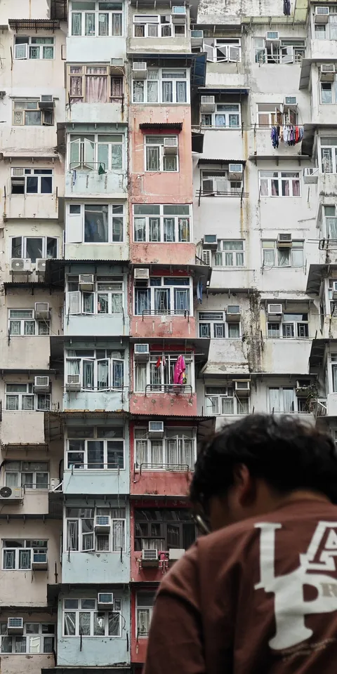A passerby below a densely packed apartment block