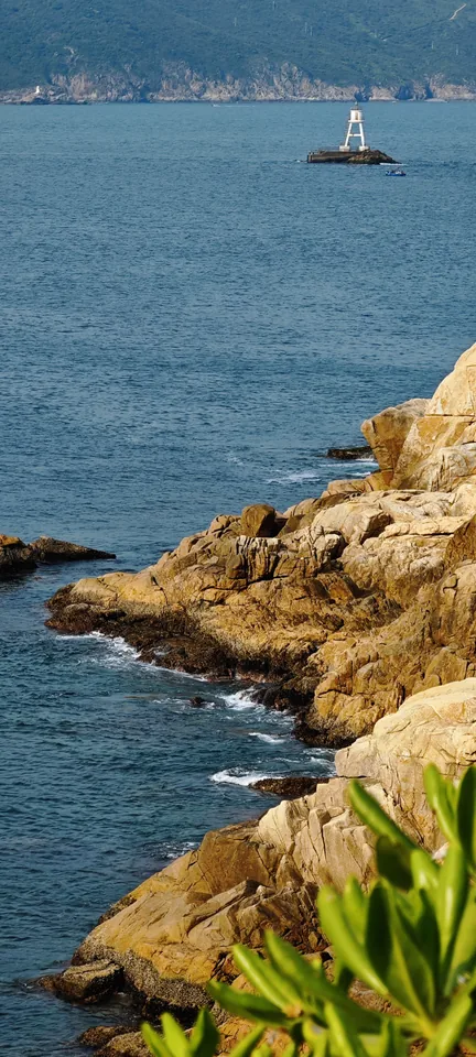 Sunlit rocks above blue water
