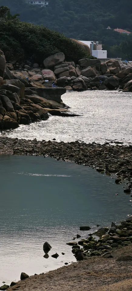 A small beach beneath a wooded hillside