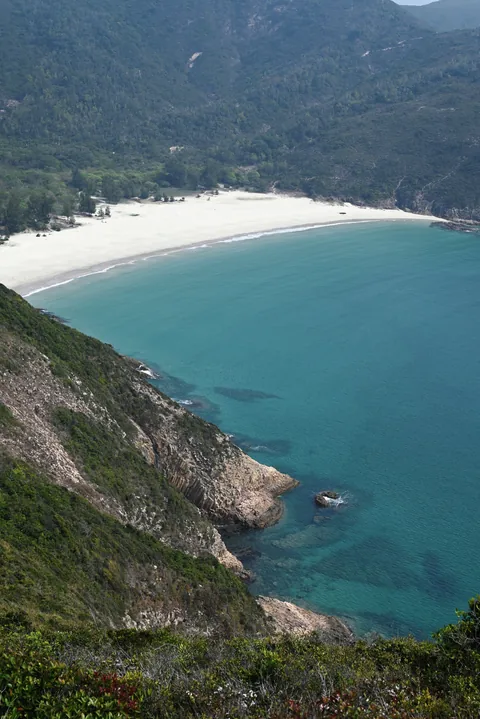 A white beach enclosed by green hills