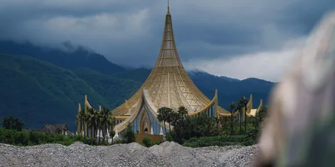 A pointed golden roof against green mountains
