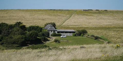 A low stone building in a coastal meadow