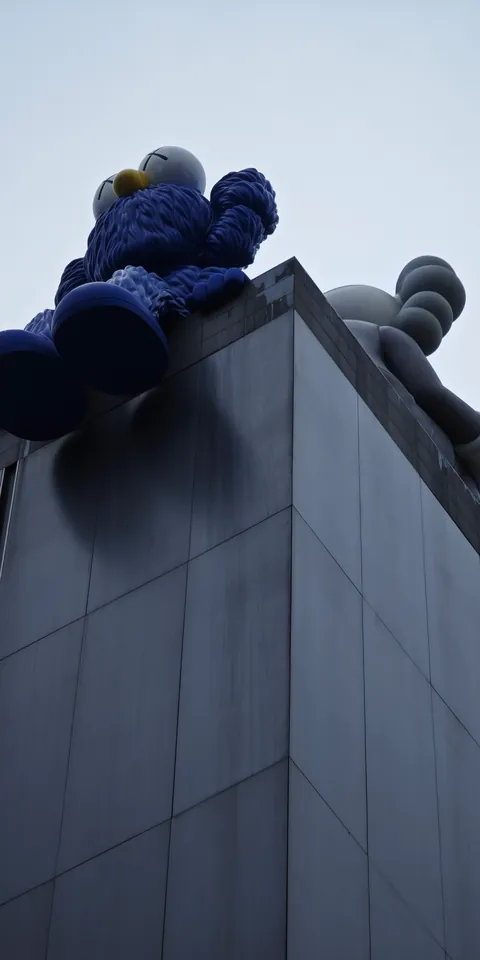 A blue figure leaning over a stone parapet