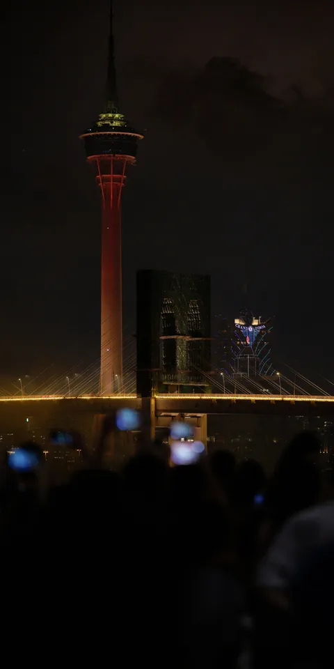 A lit tower above a nighttime crowd