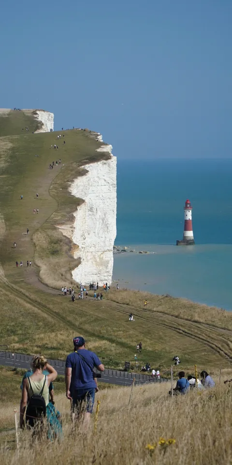 Walkers beside a white cliff and the sea