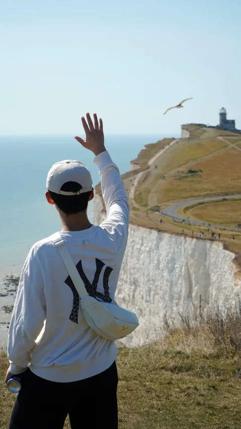 A person waving on a coastal walk