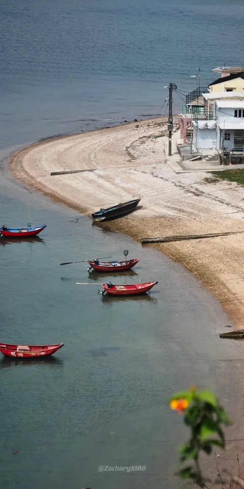 Small boats beside a curving sandy beach